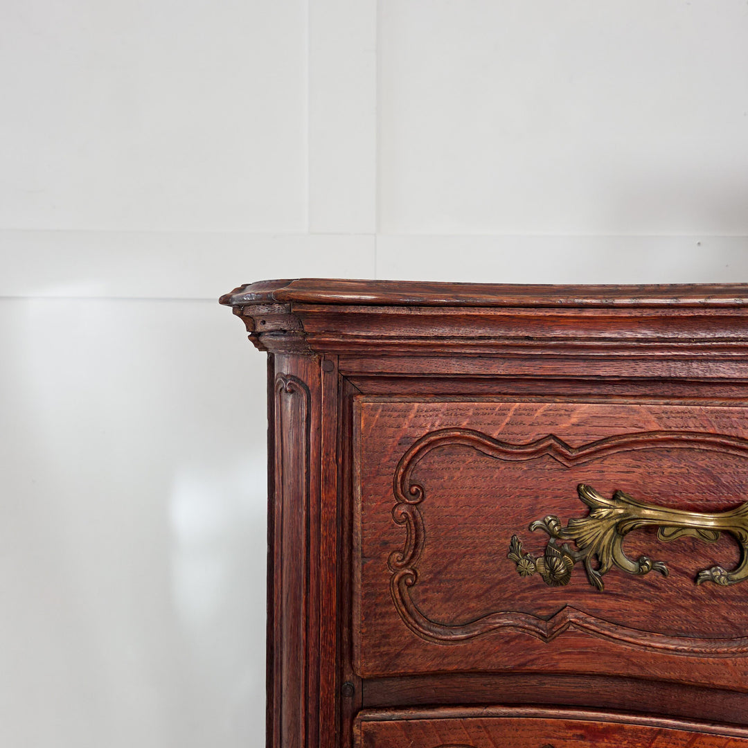 Antique French walnut serpentine chest of drawers, 19th century. This chest offers four carved drawers fitted with ornate brass handles and escutcheons. Raised on short carved legs, it is constructed in walnut with a naturally developed patina.