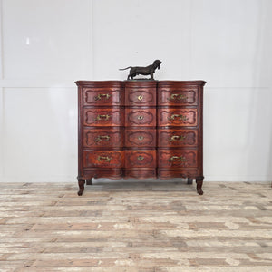 A 19th century French walnut serpentine commode, offering four large drawers with carved decoration, ornate brass handles, and escutcheons. The walnut has developed a rich patina through age, and the chest stands on short carved legs typical of French design.
