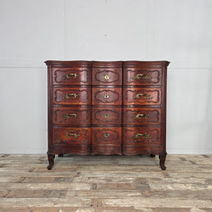 Antique French walnut serpentine chest of drawers dating to the 19th century. Constructed with four carved drawers, ornate brass handles and escutcheons, shaped serpentine fronts, and short carved feet. A substantial walnut piece with decorative carved detailing.