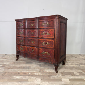 Antique French walnut serpentine chest of drawers dating to the 19th century. Constructed in walnut with four carved drawers, ornate brass handles, matching escutcheons, and raised on short carved feet with a naturally aged surface.