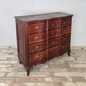 A 19th century French walnut serpentine commode with four full-width drawers. Each drawer is finished with carved decoration, ornate brass handles, and escutcheons. The piece stands on short carved feet and displays a rich walnut patina.