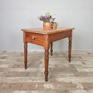 A small Victorian pine farmhouse table with a rustic stripped pine top, rounded edges, and turned legs, complete with a single drawer and wooden knob. Perfect as a country pine kitchen table, compact dining table, or useful side table in a hallway or living room.