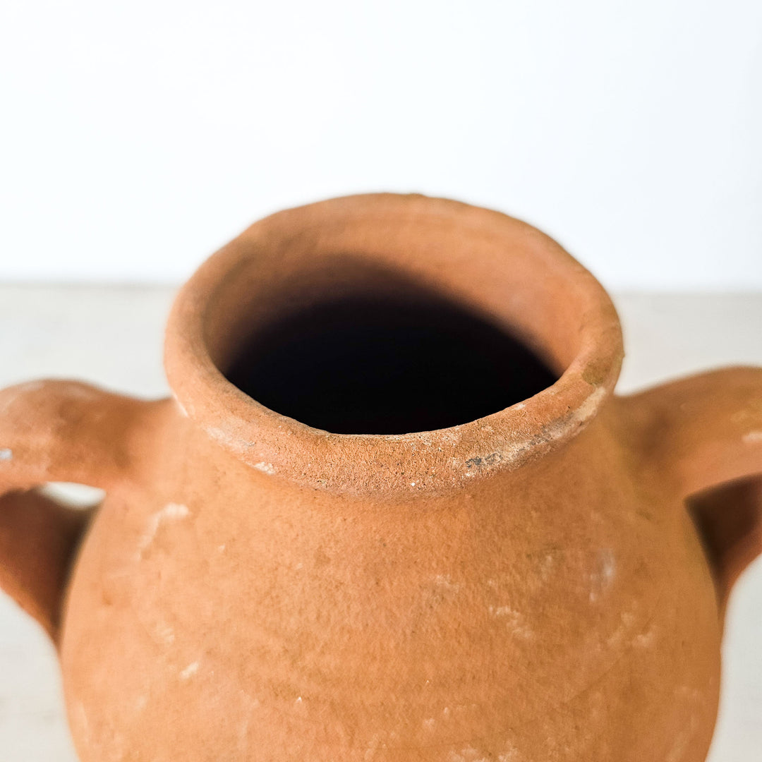 Small terracotta jar with two handles, perfect for rustic décor.