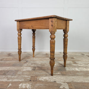 An early 19th-century small antique pine farmhouse table with a two-plank top and rounded edges, set on decorative turned legs that have been extended with newer timber. The simple apron and pine construction create a useful country-style table for hallways or small kitchen areas.
