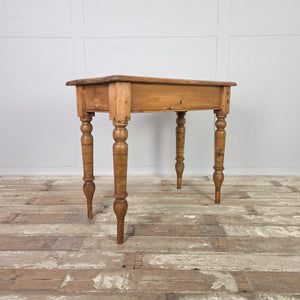 A small antique pine farmhouse table featuring a two-plank rectangular top with rounded edges, supported by turned legs extended at the base with later timber. Finished with a simple apron, this country-style piece offers a practical pine surface suitable for hallways or smaller kitchen spaces.