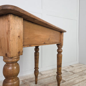 A 19th-century small antique pine farmhouse table with a two-plank top, rounded edges and a simple apron. The turned legs, extended with newer timber, support this practical country-style pine table suited to hallways or limited kitchen spaces.