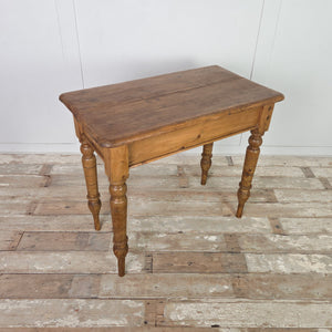 A small antique pine farmhouse table with a two-plank rectangular top, rounded edges and a simple apron. Raised on turned legs extended at the base with later timber, this country-style table offers functional pine surface space for hallways or small kitchen settings.