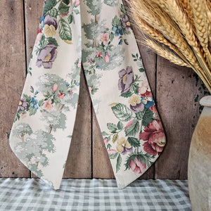 Chic floral patterned bow with pastel blooms on a natural background."