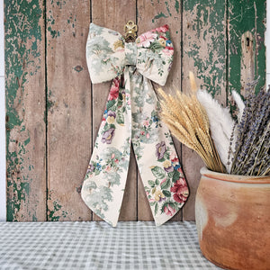 Vintage Sanderson floral bow with brass ring against rustic wooden backdrop