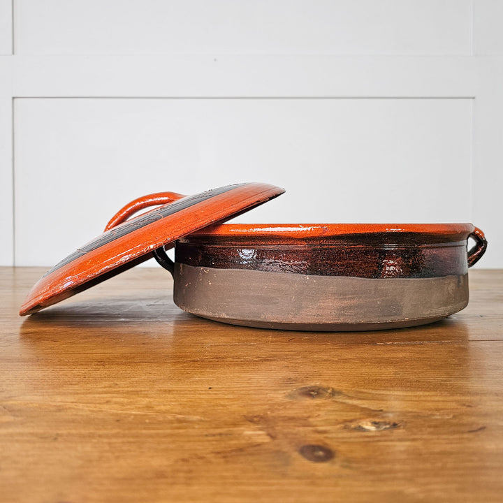 Vintage glazed cooking pot with handles for easy carrying.
