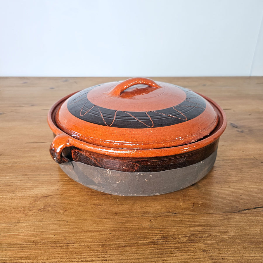 Vintage Spanish terracotta cooking pot with black and orange glaze.
