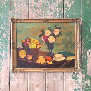 The antique oil painting still life is a 19th century signed work showing a floral and fruit arrangement, presented in a decorative gilt frame, and typical of Victorian artwork for home interiors.
