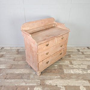 An antique pine chest of drawers dating from the Victorian period, constructed with four drawers in a two-over-two layout. The piece features decorative brass drawer handles, a shaped gallery back, and turned tulip bun feet.