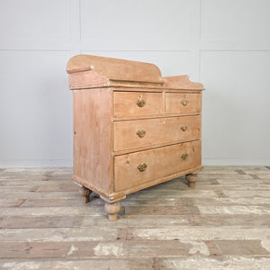 A Victorian antique pine four drawer chest with a two-over-two drawer arrangement and decorative brass handles. The chest includes a shaped gallery back designed to prevent items falling behind the piece and is raised on tulip bun feet.