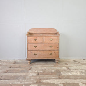 A Victorian pine bedroom chest of drawers from the 19th century with four drawers in a two-over-two arrangement. Decorative brass handles, a shaped gallery back, and turned tulip bun feet define the construction.