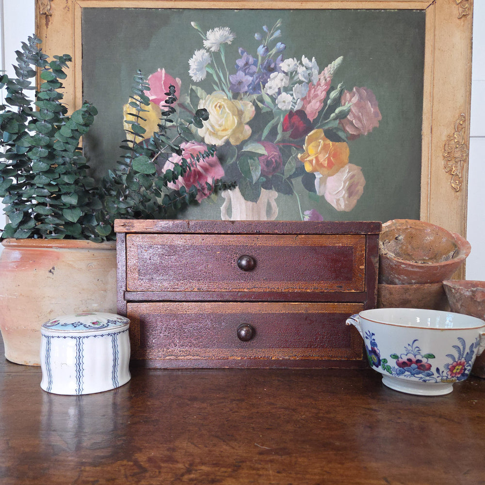 Victorian antique tabletop drawers made from pine with two drawers and wooden knobs. The original painted finish in warm reddish-brown with lighter borders shows gentle wear, making this small chest of drawers perfect for country house style interiors.
