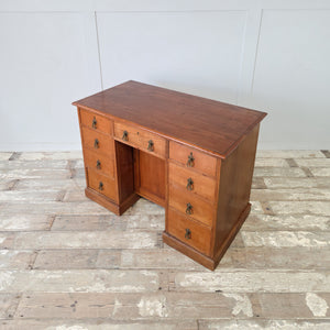 Antique nine drawer cherrywood desk with a recessed kneehole cupboard and plinth base
