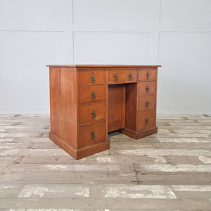 Antique cherrywood desk with nine drawers arranged around a recessed central kneehole cupboard
