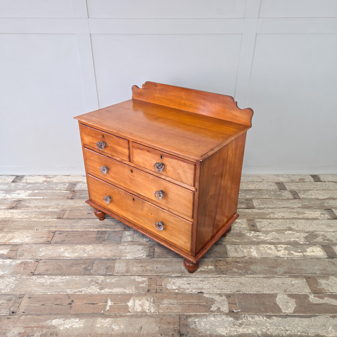 Antique Victorian four drawer chest of drawers in mahogany with original glass knobs, shaped upstand and turned bun feet, the two short over two long arrangement providing a deep lower drawer for ample storage, a 19th century chest ideal as bedroom furniture or hallway drawers.