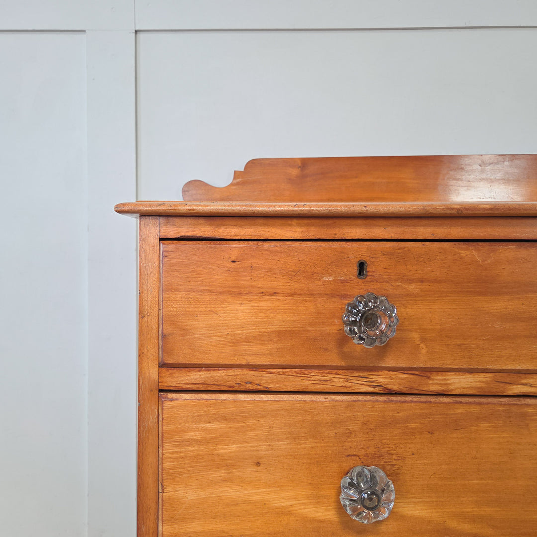A Victorian four drawer chest in mahogany with two short over two long arrangement, graduated drawers fitted with original glass knobs, shaped upstand to the top, and bun feet, a versatile antique chest of drawers from the 19th century, well-made and ideal for bedroom or hallway storage.
