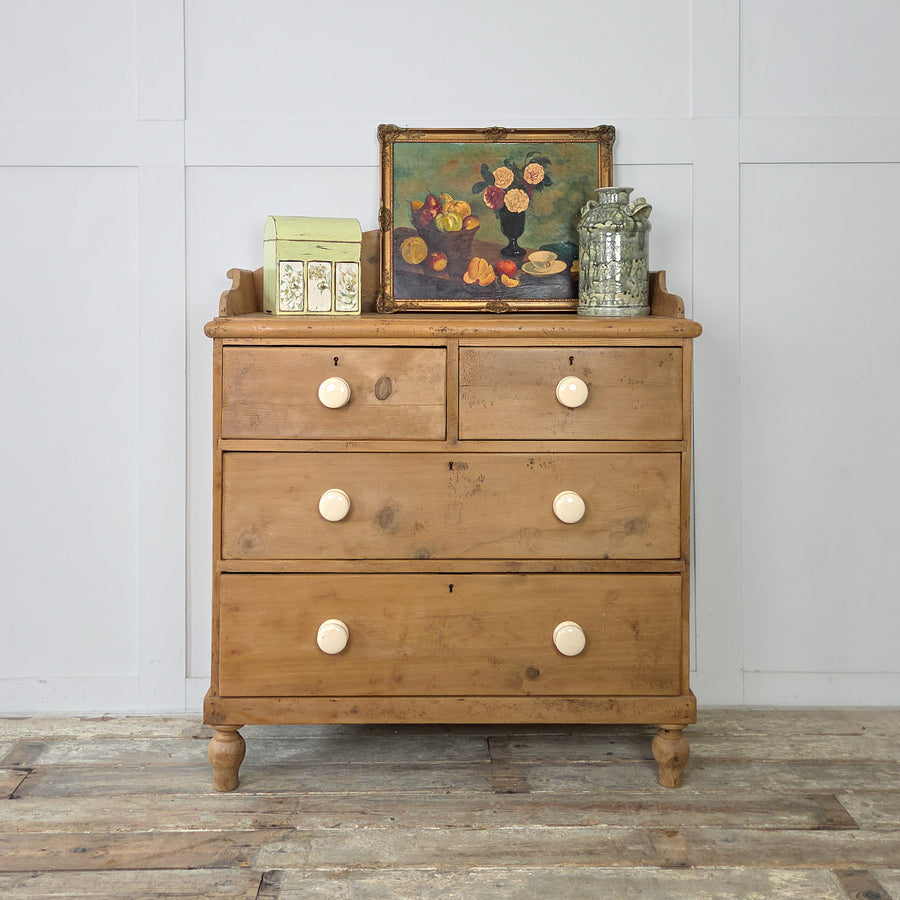 A Victorian pine chest of drawers with shaped gallery back and bun feet, classic bedroom storage with decorative appeal