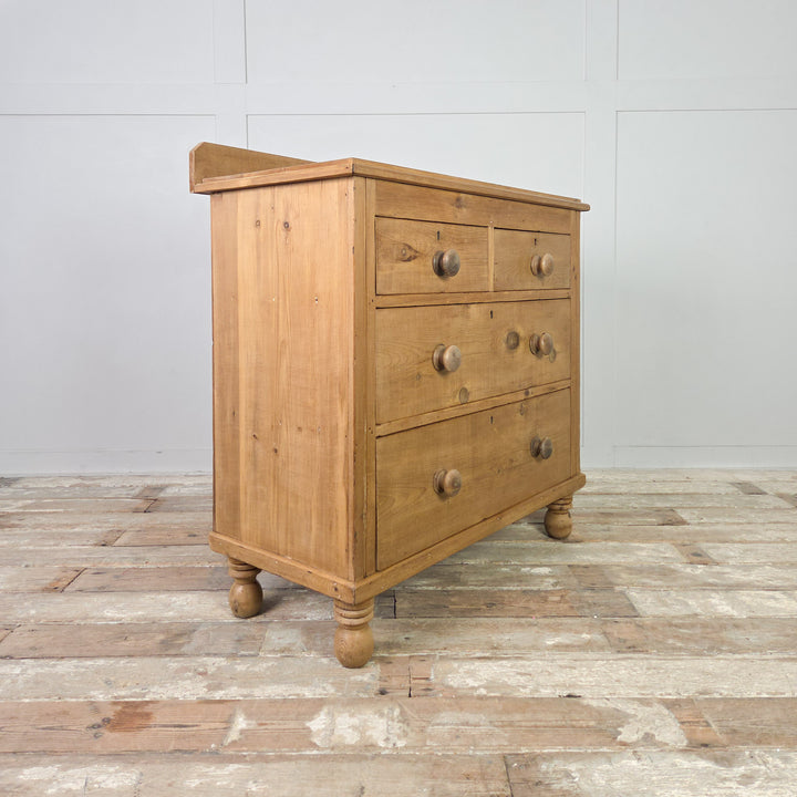 A late 19th-century Victorian pine chest of drawers with four drawers in a two-over-two layout, standing on traditional bun feet and sealed in clear wax to enhance its mellow patina, offering useful antique storage for the home.