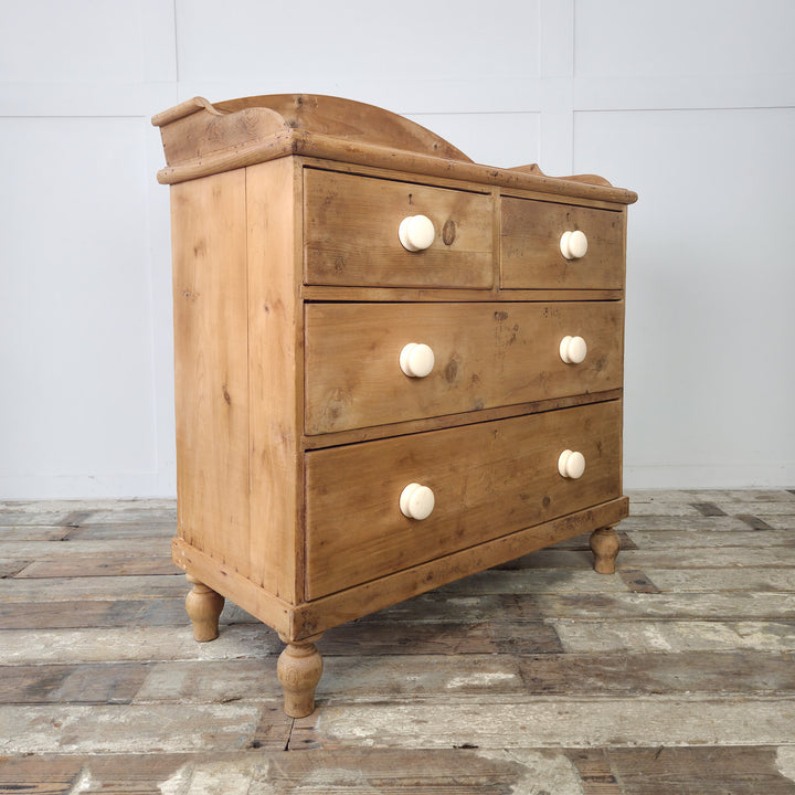 A Victorian pine bedroom drawers unit with large ceramic knobs and a raised gallery back, blending functionality with heritage style