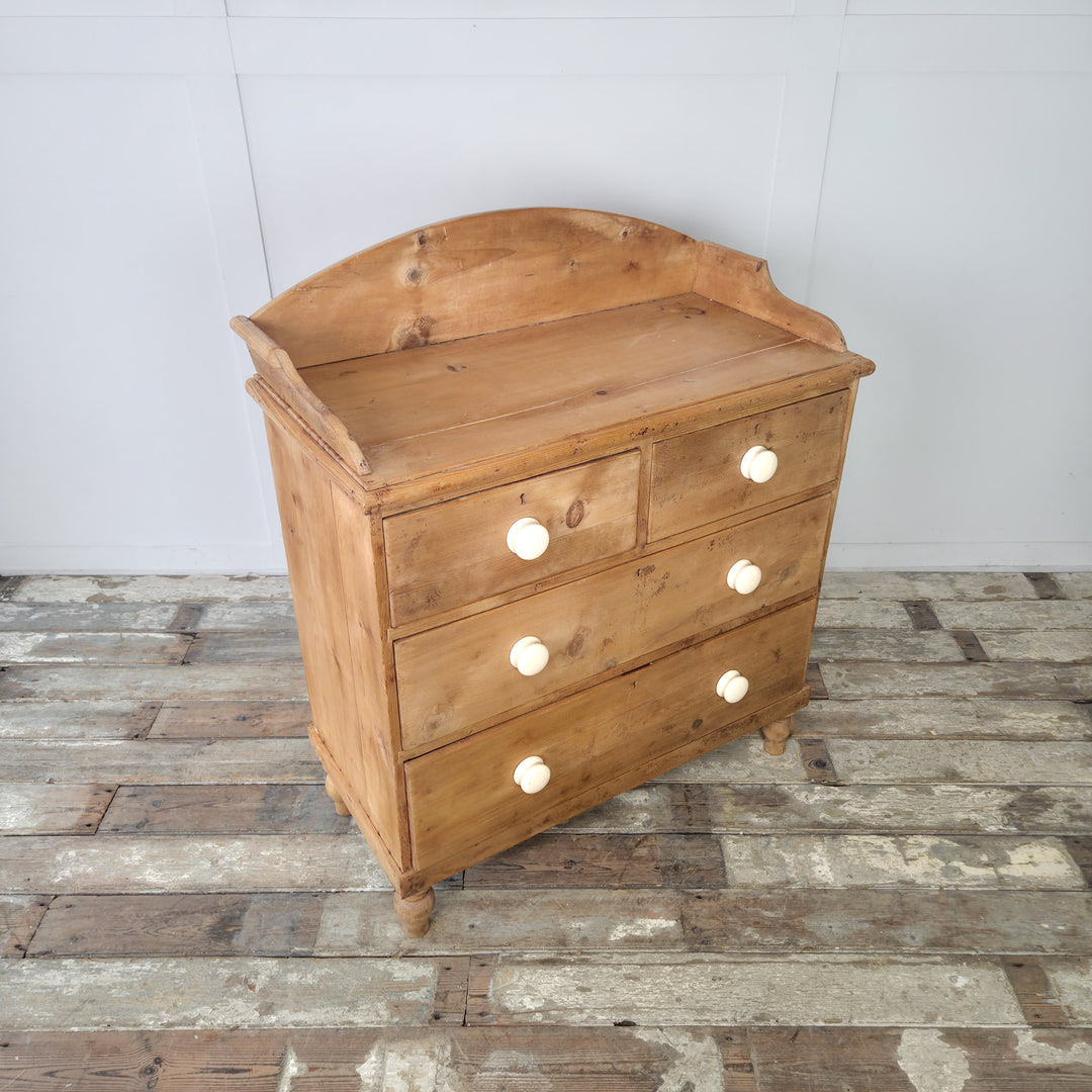 An antique pine chest of drawers with bun feet and shaped gallery back, ideal for storing clothing, linens, or household items