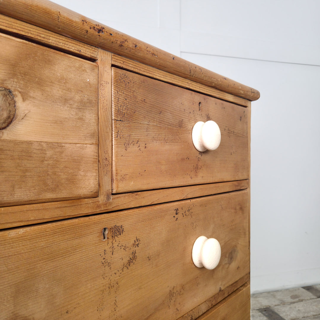 A 19th century chest of drawers in solid pine, featuring decorative gallery back and ceramic knobs, perfect for home organization