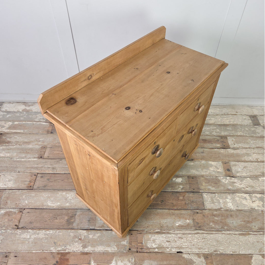An antique pine Victorian chest of drawers with original knobs and bun feet, offering four well-sized drawers and a warm waxed surface that highlights the grain and natural patina of the pine.