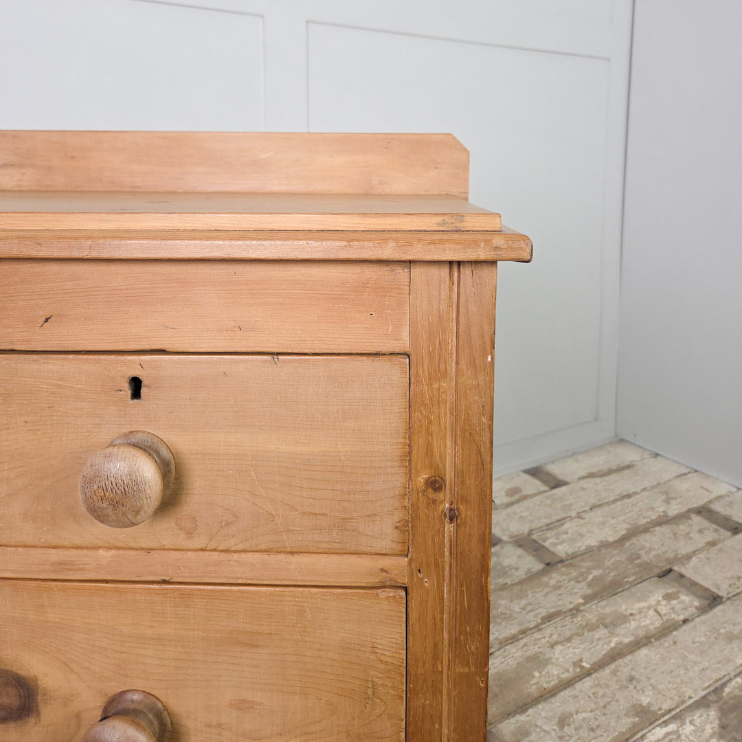 A Victorian pine dresser or chest of drawers from the late 1800s, featuring four drawers and bun feet, waxed to protect its surface and showcasing the simplicity and craftsmanship of 19th-century furniture.