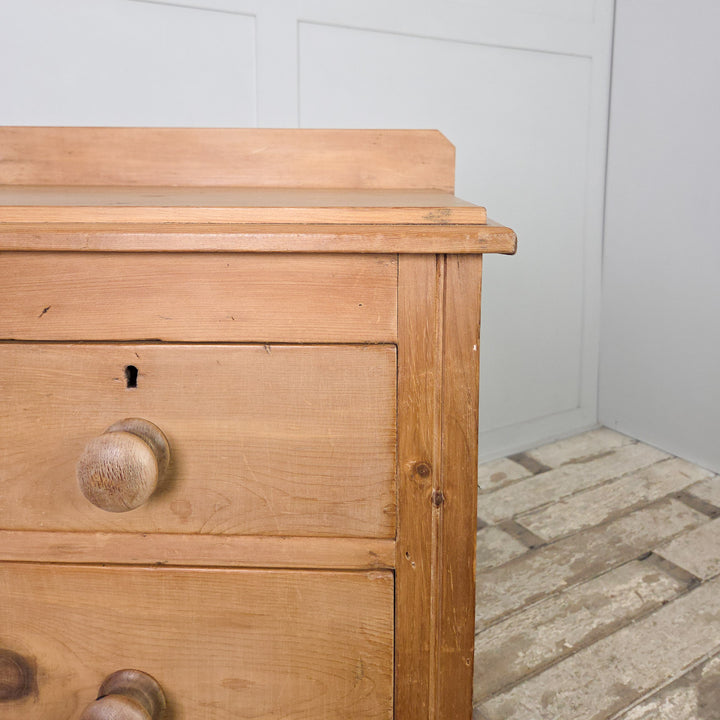 A Victorian pine dresser or chest of drawers from the late 1800s, featuring four drawers and bun feet, waxed to protect its surface and showcasing the simplicity and craftsmanship of 19th-century furniture.