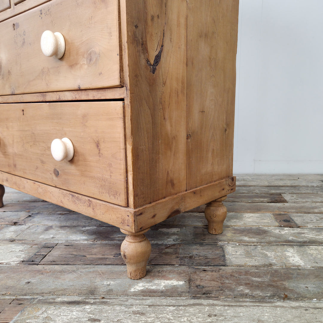 A four-drawer antique chest of drawers in pine, featuring bun feet and detailed gallery back, suited to multi-room placement