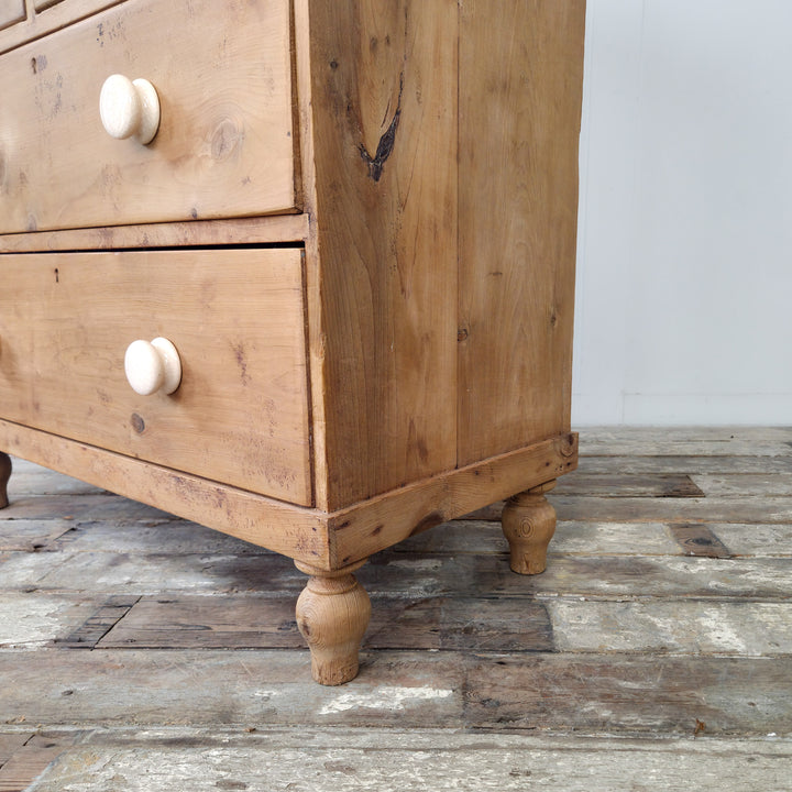 A four-drawer antique chest of drawers in pine, featuring bun feet and detailed gallery back, suited to multi-room placement