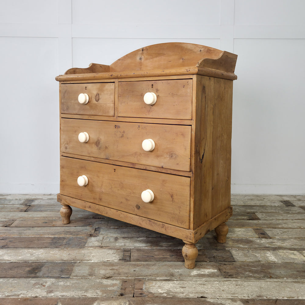 A 19th century pine chest of drawers featuring four spacious drawers and ceramic knobs in a warm honey-toned finish

