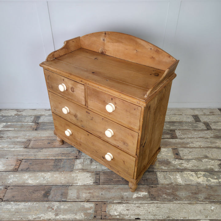 An antique pine chest with gallery back and bun feet, offering stylish storage solution for bedrooms, hallways, or living rooms
