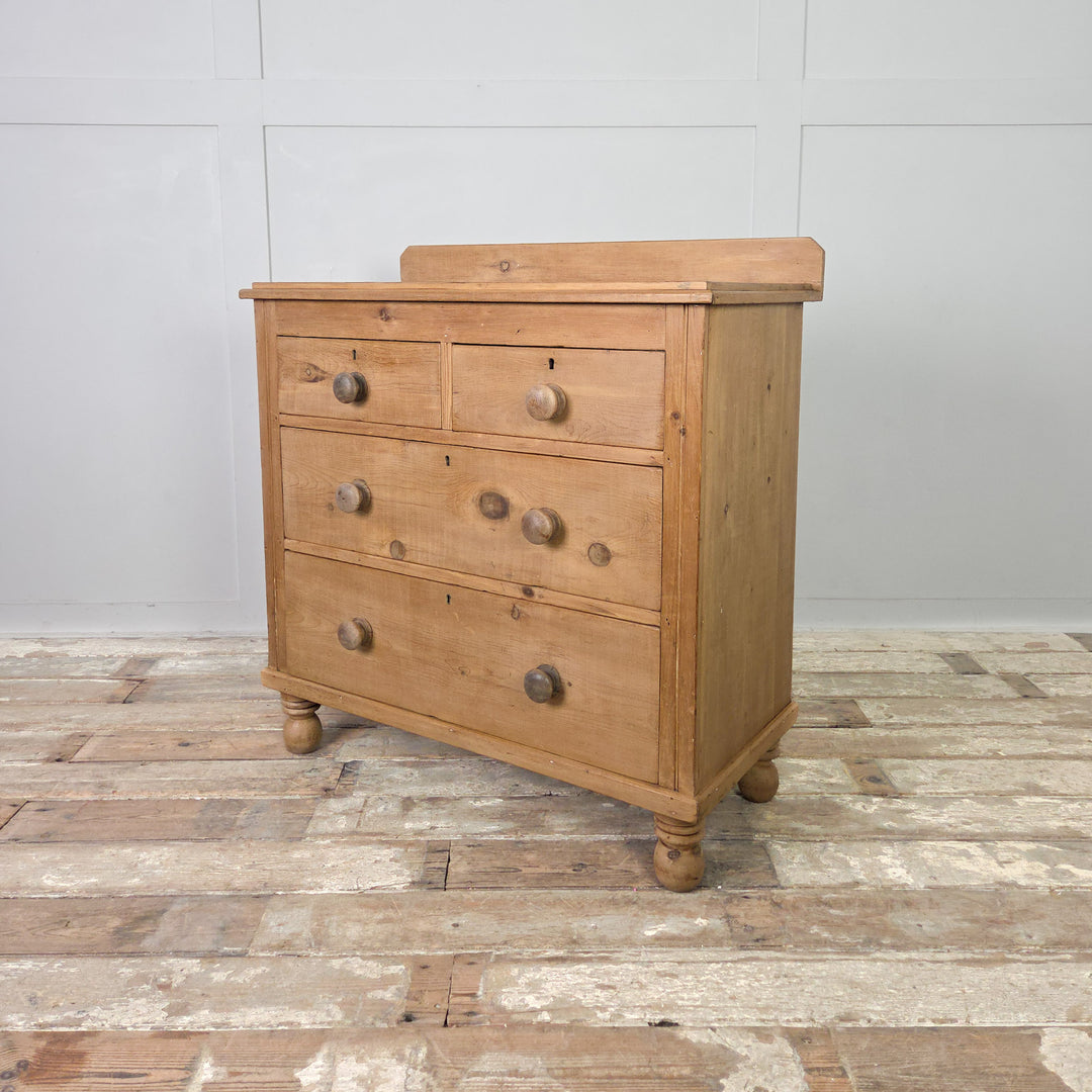 An antique pine storage chest from the Victorian period, with four drawers, bun feet and a clear wax finish, providing elegant and practical storage for any living or bedroom space.