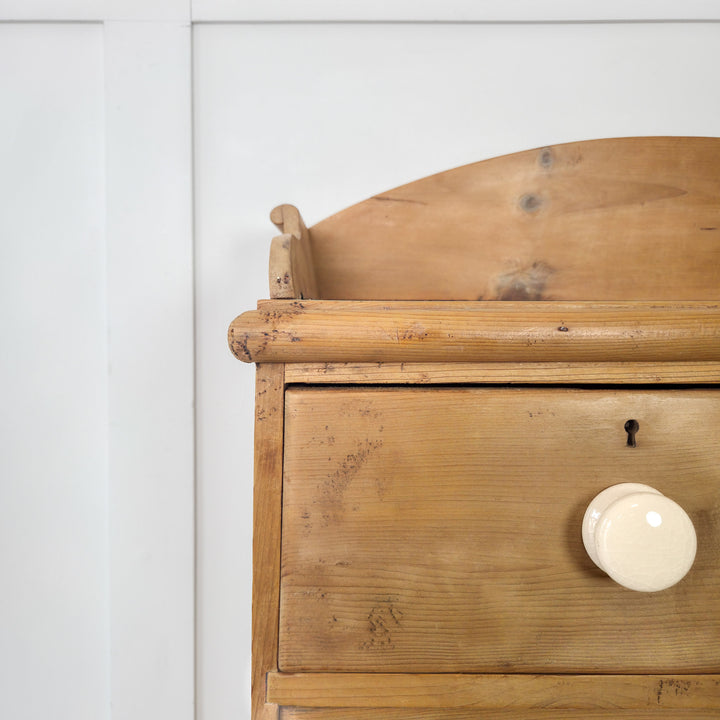 A classic four-drawer pine chest of drawers with gallery back and bun feet, providing timeless style and cupboard space