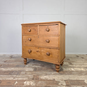 A Victorian pine chest of drawers from the 19th century with a classic two over two arrangement, raised on turned bun feet. Finished in waxed pine, this antique storage chest combines practical four-drawer storage with the natural patina of aged wood, making it ideal for farmhouse interiors, country house bedrooms or rustic kitchen storage.