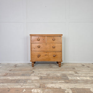 A Victorian pine chest of drawers from the 19th century with a classic two over two arrangement, raised on turned bun feet. Finished in waxed pine, this antique storage chest combines practical four-drawer storage with the natural patina of aged wood, making it ideal for farmhouse interiors, country house bedrooms or rustic kitchen storage.