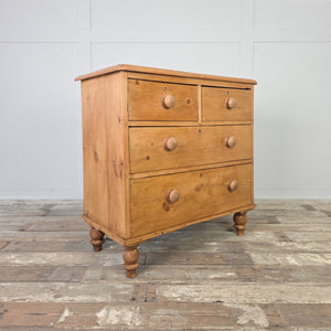 A 19th century Victorian pine chest of drawers offering storage with two smaller drawers over two deeper drawers, all set on turned bun feet. The waxed pine patina highlights the natural grain, while the versatile scale makes this antique chest suitable for farmhouse bedrooms, rustic living rooms or as a sideboard in kitchens styled with country decor.