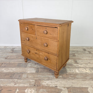 Victorian antique pine chest of drawers with four drawers in a two over two layout, turned bun feet and a waxed pine finish. This 19th century piece provides both function and character, making it ideal for antique bedroom storage, rustic farmhouse interiors, or country house living spaces where warm, natural wood furniture enhances traditional design schemes.