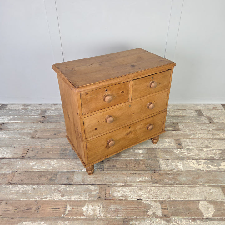 An antique Victorian pine chest of drawers, 19th century in date, with four drawers raised on bun feet. Later wooden knobs add a simple touch, while the waxed pine surface enhances the natural patina. Perfect for farmhouse bedrooms, rustic interiors or country house kitchens, this chest combines characterful antique storage with versatile styling options.