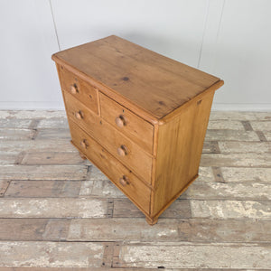 Antique pine chest of drawers from the Victorian era, designed with two short drawers above two long drawers, bun feet and a waxed patina. A practical and attractive 19th century furniture piece, it works beautifully in country house bedrooms as clothing storage, rustic farmhouse kitchens as a sideboard, or as antique living room furniture with character.