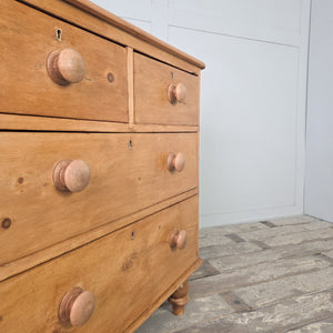 An antique Victorian pine chest of drawers from the 19th century with four drawers arranged two over two, raised on bun feet. Featuring later added wooden knobs and a waxed pine finish, this chest brings warmth and storage to bedrooms, living rooms and kitchens styled with rustic farmhouse furniture, country house decor and traditional interiors.