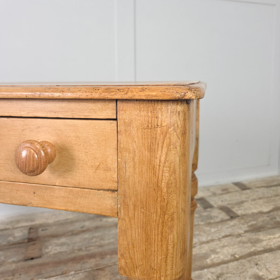 A late Victorian pine console table or writing desk with a simple, practical design, complete with two drawers and a natural waxed finish that brings out the warmth of the original pine.


