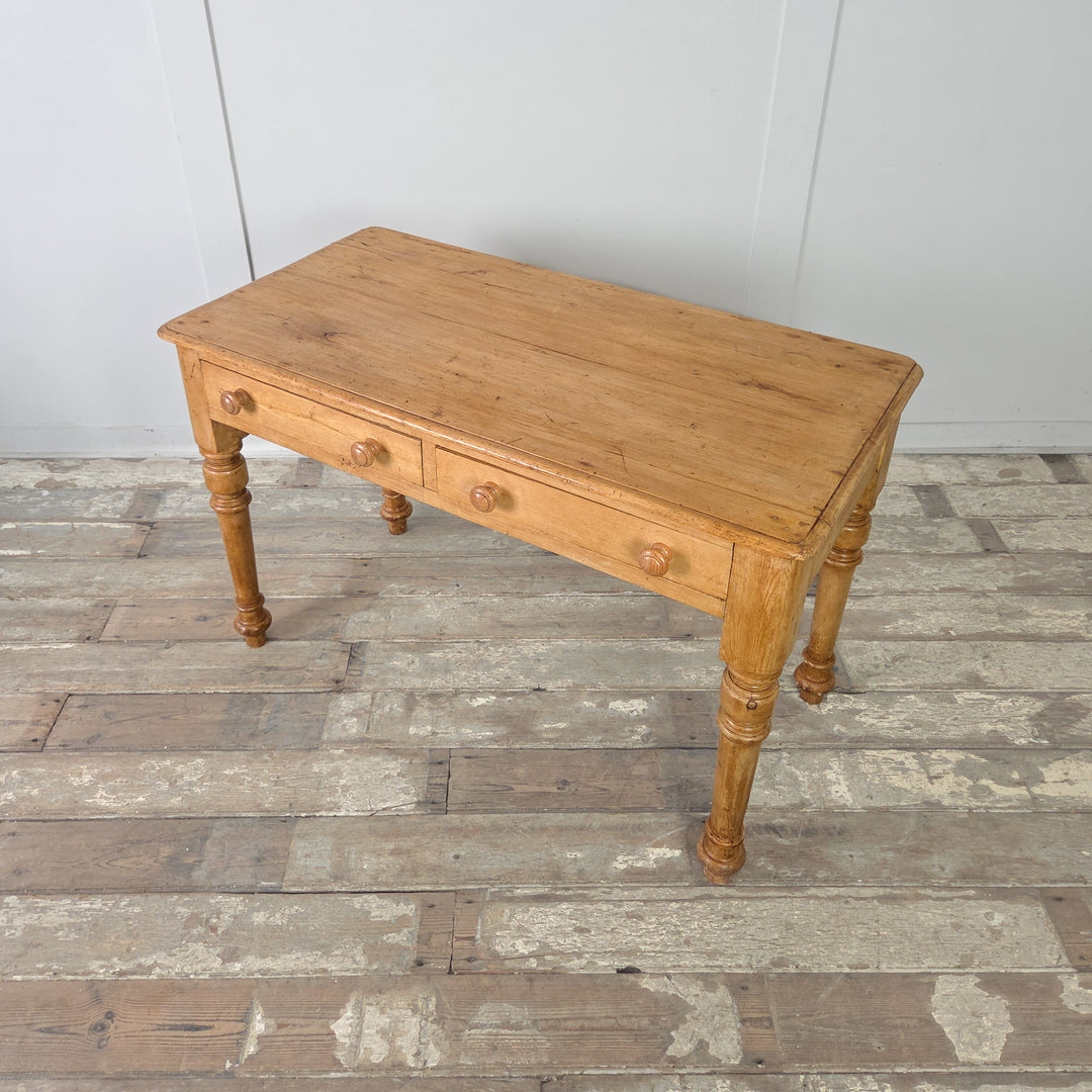 The antique Victorian pine console table shown with its honey-toned waxed finish, two drawers with wooden knobs, and plain apron construction. A versatile piece for hallways, studies, or bedrooms.

