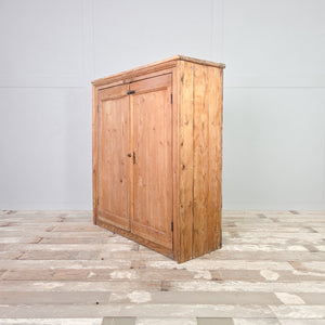 Antique pine cupboard from the Victorian era, showing two panelled doors with brass fittings and four internal shelves arranged across the full width of the cupboard.
