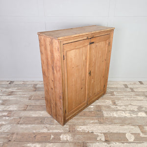 Antique pine cupboard from the Victorian period, showing panelled doors with brass hardware and internal shelving arranged for practical storage.
