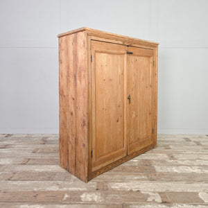 Victorian pine cupboard with two panelled doors, brass locking hardware, and four internal shelves set within a simple, rustic farmhouse form.
